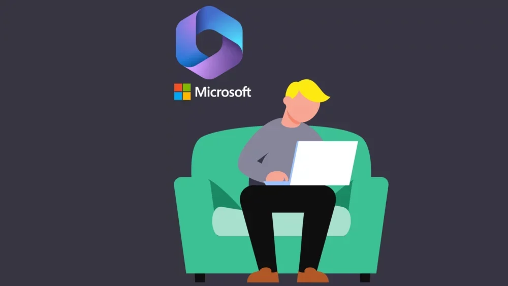 Man sitting on sofa looking at laptop with Microsoft icon in back