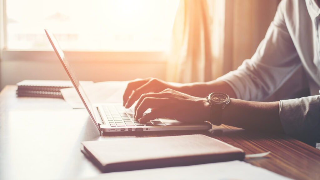 Close-up of male hands using laptop in home.